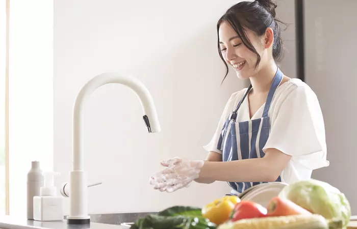 Женщина моет руки перед приготовлением еды, чтобы оставаться здоровой
