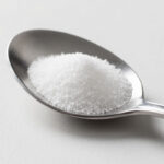 Чайная ложка белого сахара крупным планом.