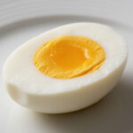 Вареное куриное яйцо в разрезе на тарелке