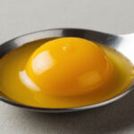 Яркий яичный желток в ложке крупным планом