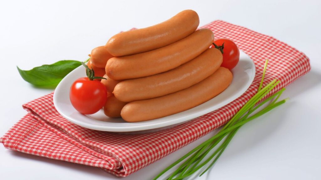 Аппетитные отварные сосиски на белой тарелке