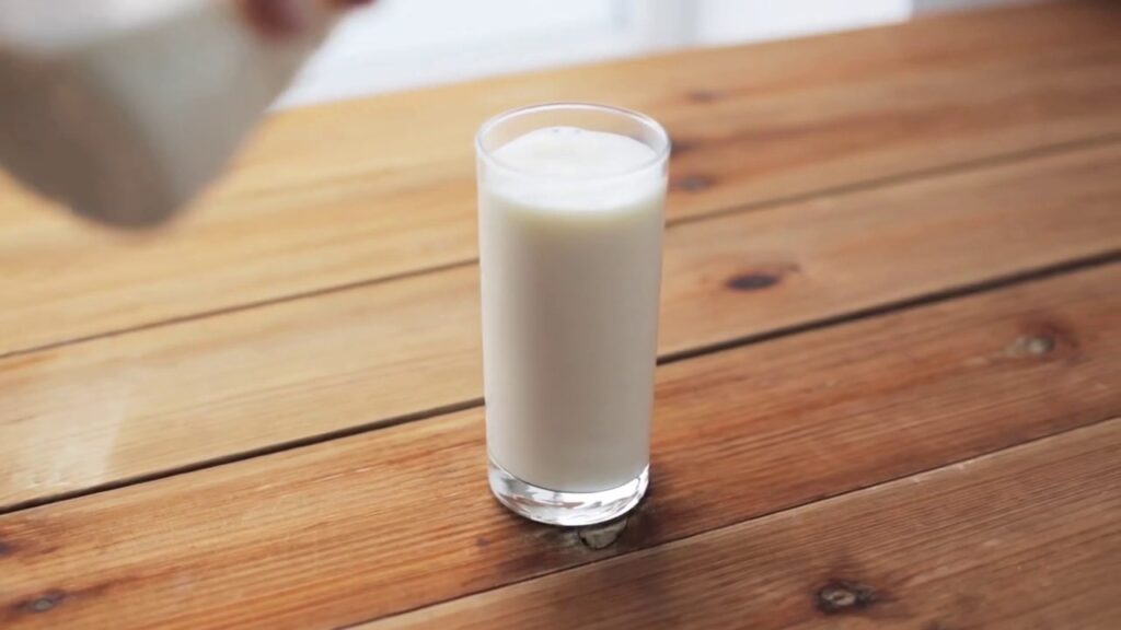 Стакан густой ряженки на деревянном столе