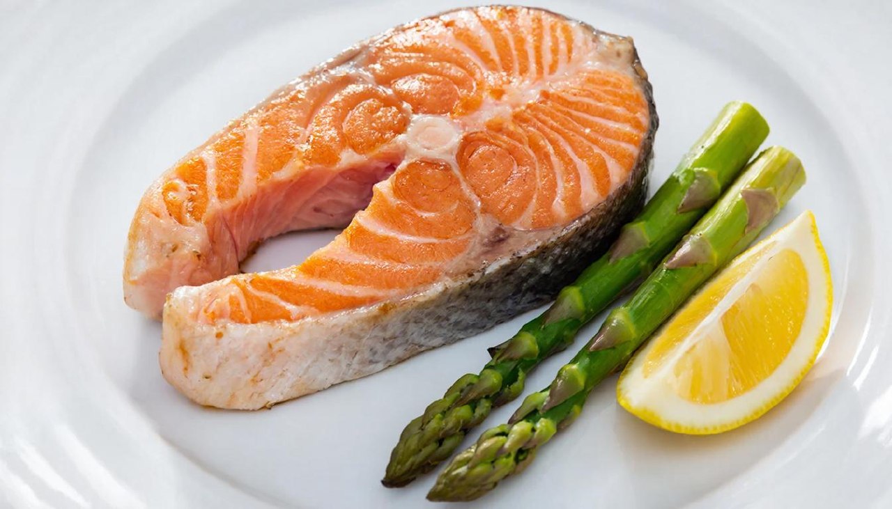 Запеченный стейк лосося с лимоном и спаржей на тарелке
