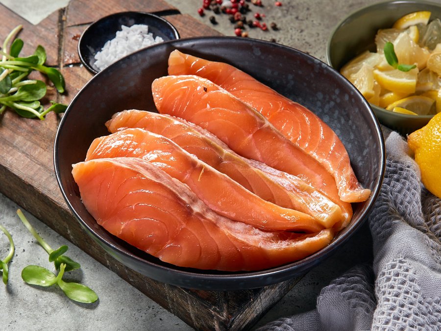 Ломтики слабосоленой семги с лимоном на деревянном фоне